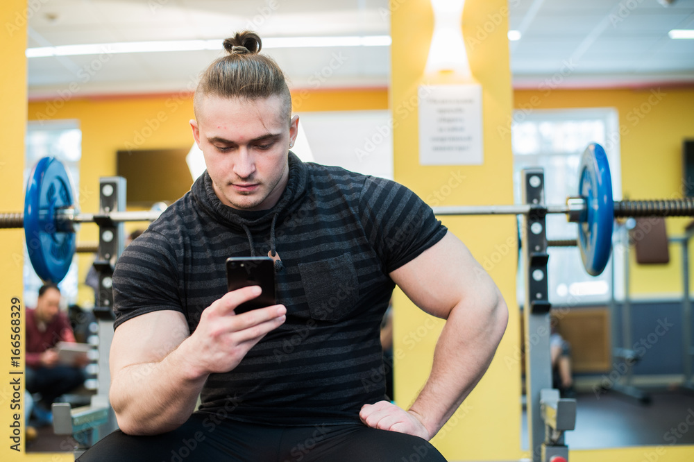 Handsome guy text messaging on his smartphone at gym. Handsome guy text messaging on his smartphone at gym.