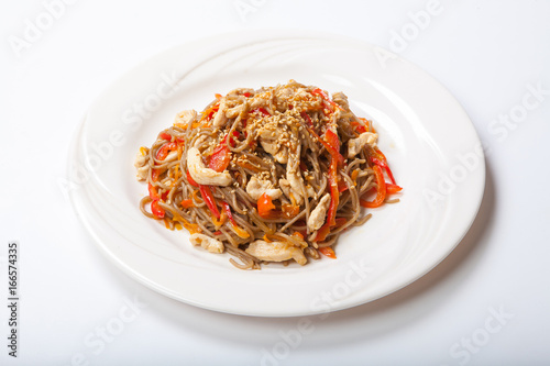 Italian pasta with chicken and peppers in a white plate on a light background