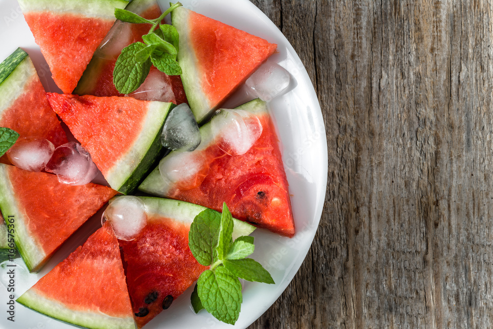 Watermelon slices, fresh summer fruit on plate, closeup and top view on wooden background