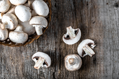 Fresh champignon mushrooms in a basket on wooden table, overhead