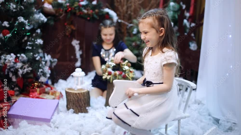 A girl is riding a wooden horse near a Christmas tree Granddaughters pack a white shawl as a present to their beloved grandmother in a gift box. A girl is riding a wooden horse near a Christmas tree Granddaughters pack a white shawl as a present to their beloved grandmother in a gift box.