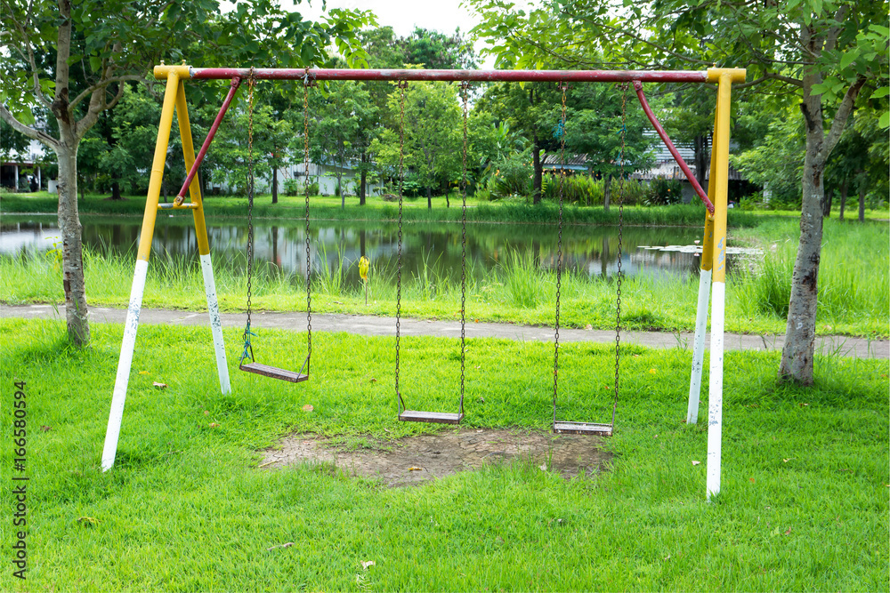 Chain swing in the park.Empty chain swing at the playground with grass background Chain swing in the park.Empty chain swing at the playground with grass background