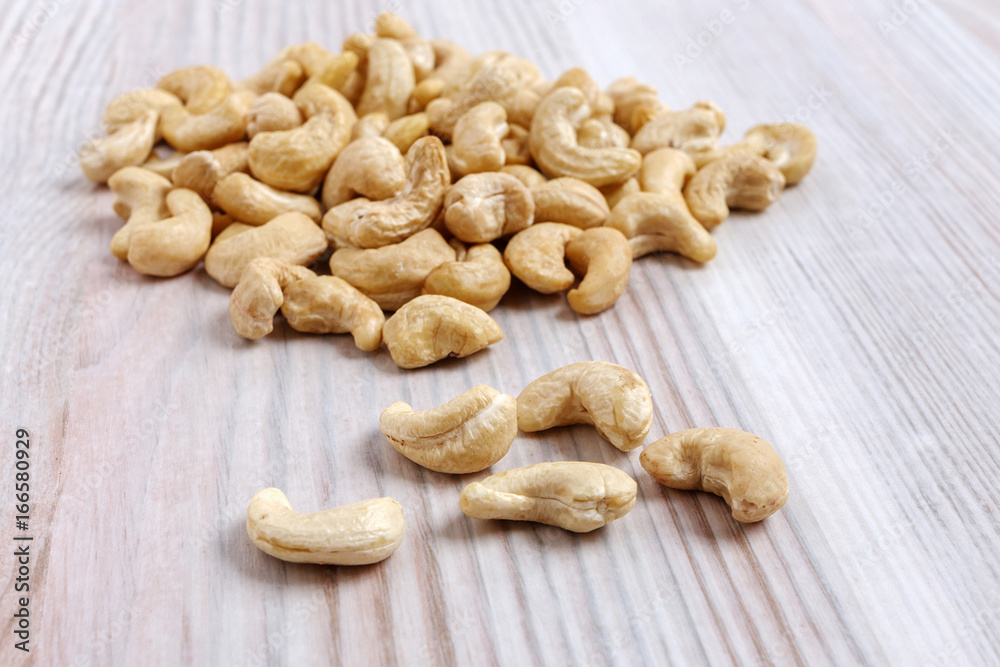 A heap of cashew nuts on a light kitchen table close-up. A heap of cashew nuts on a light kitchen table close-up.