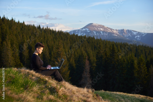 Shot of a young woman taking in the view while sitting with her laptop on top of a hill copyspace camping hiking travel tourism internet online connection mobility.