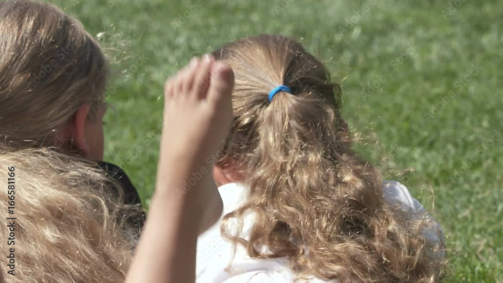 Children relaxing on green grass in the backyard. Close-up of children ...