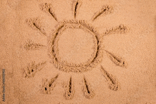 Sun drawn in soft wet sand on a beach