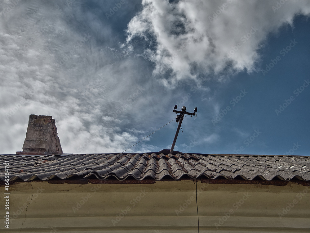 The antenna on the roof of the old house.