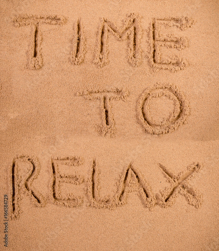 Time to relax written in soft wet sand on a beach