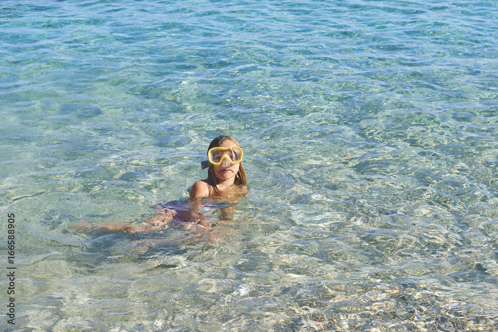 Child little girl wearing diving goggles in the sea. Portrait of a cute girl wearing a goggles for diving background of the sea