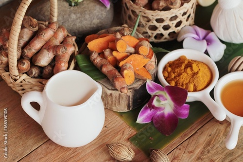 Turmeric root with turmeric powder on wood background