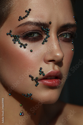 Woman portrait with pearl beads on her skin. Creative makeup