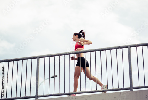 Female runner jogging on the city street by the traffic road.City environment.