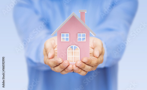Small pink toy house in hands 