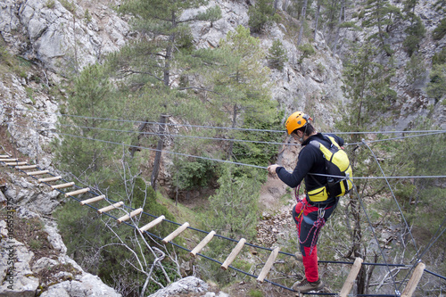 mountaineer crossing a bridge of a via ferrata