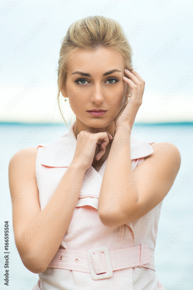 Young girl sitting on the beach in the sea background.