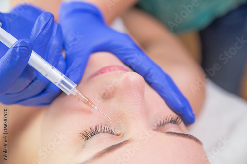 Beautiful young woman gets beauty injection in eye area