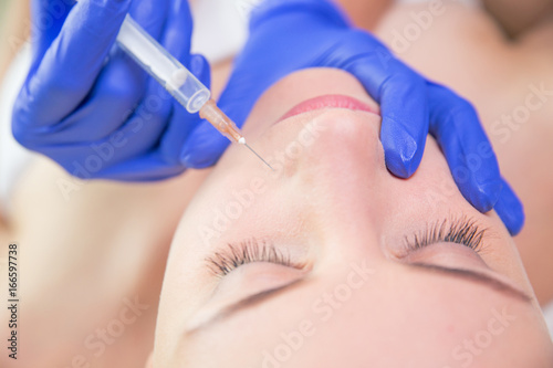Close-up of beautiful woman's face with syringe
