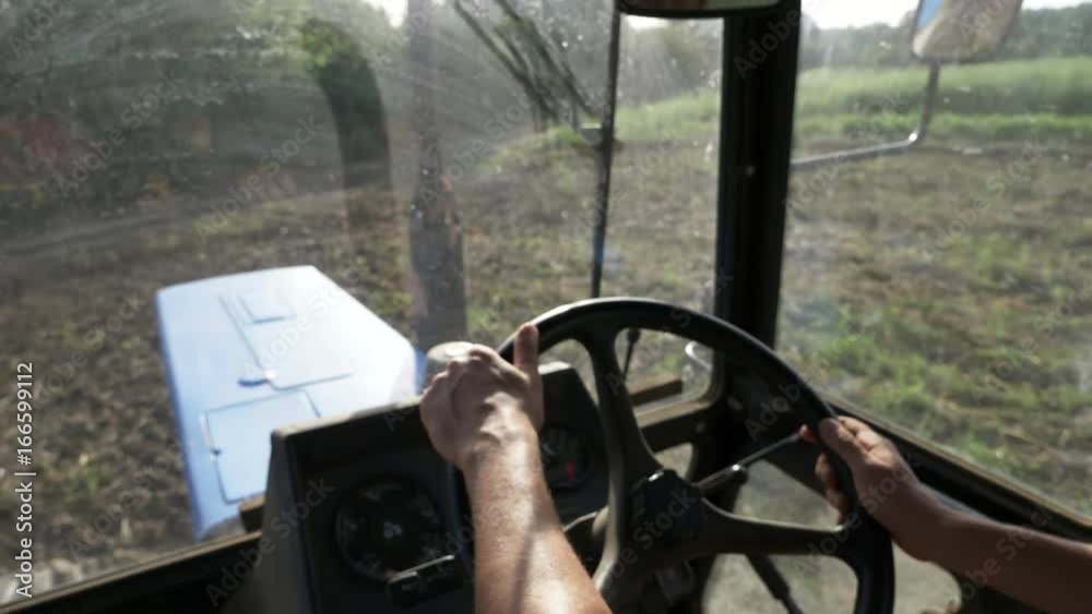 Farmer in hat, sits inside in the tractor cabin, rides on the field with plow. Farmer in hat, sits inside in the tractor cabin, rides on the field with plow.