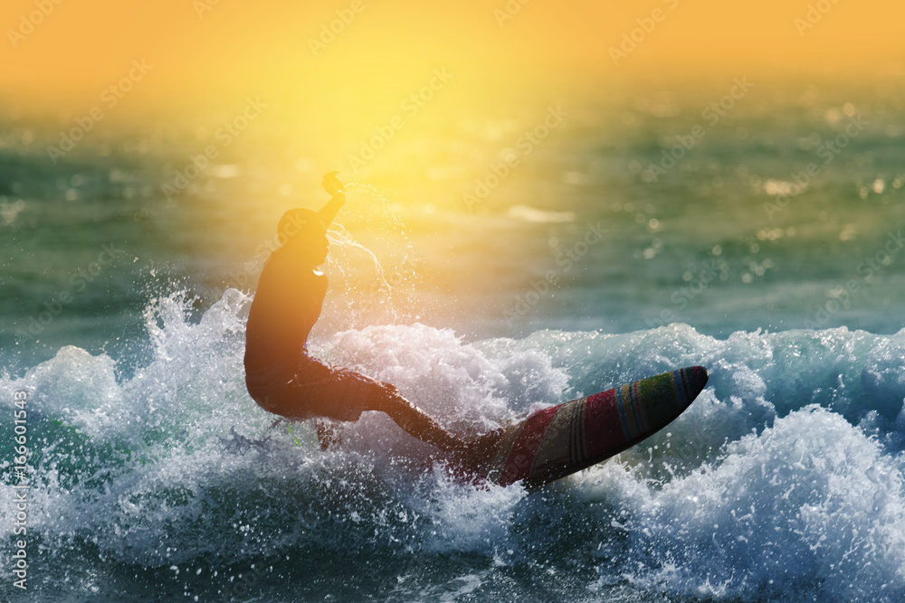 Silhouette surfing at sunset.Happy surfer enjoy big wave during vacation in tropical island.