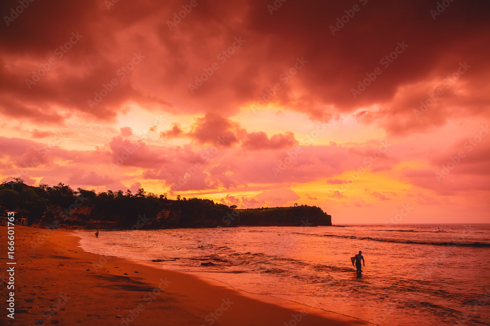 Red sunset, surfers and ocean in Bali, Balangan