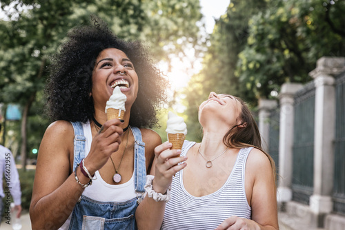 Beautiful women eating one ice cream in the street.