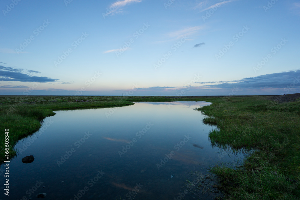 Iceland - Reflecting clouds and sky in twilight mood with awesome landscape