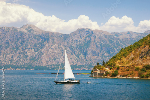 One boat sails along Kotor Bay on a summer day. Montenegro