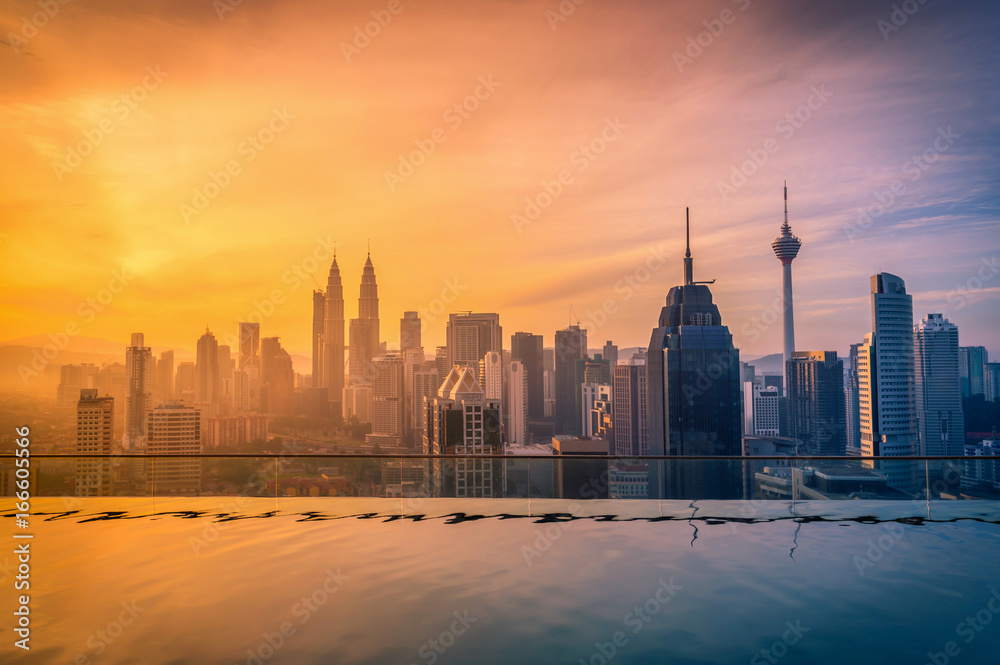 Fototapeta premium Pejzaż panoramę miasta Kuala lumpur z basenem na dachu hotelu o wschodzie słońca w Malezji.