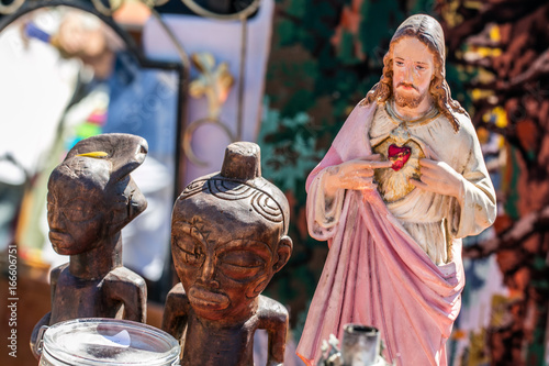 polytheism religion symbols, Christ and wooden African statues at garage sale photo
