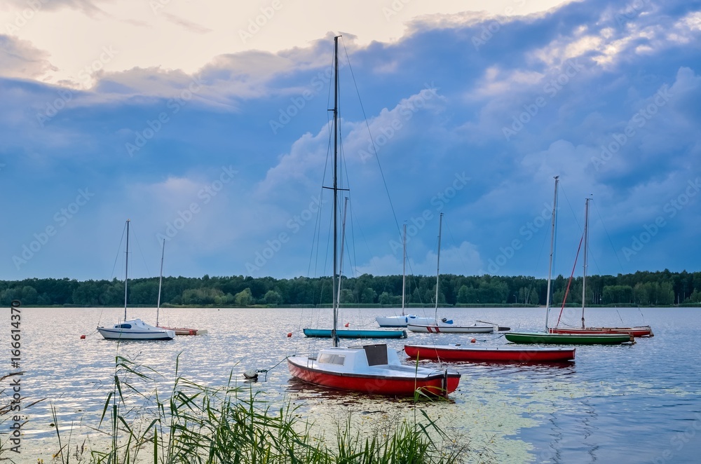 Summer evening landscape. Boats on the lake and colorful sky.