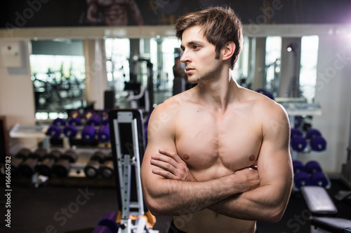 Muscular man working out in gym doing exercises at triceps, strong male naked torso abs. Fitness