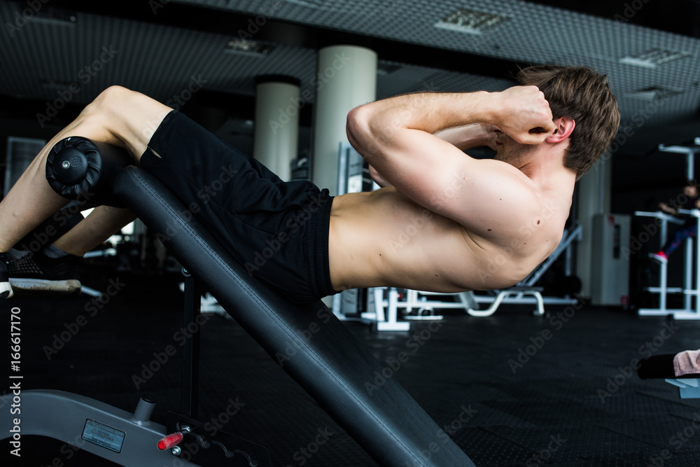 Muscular man exercising doing sit up exercise.
