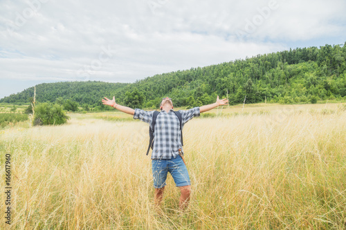 Man hiker with arms wide open in the wheat-field.