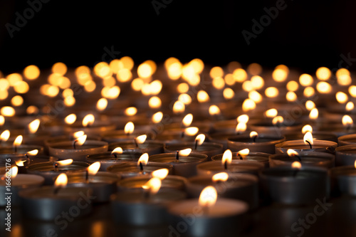 Flaming candles. Spiritual image of tealights providing sacred light. Romantic candlelight at night.
