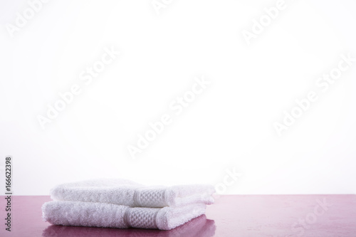 Spa. Two white towels on a pink marble table. White background.