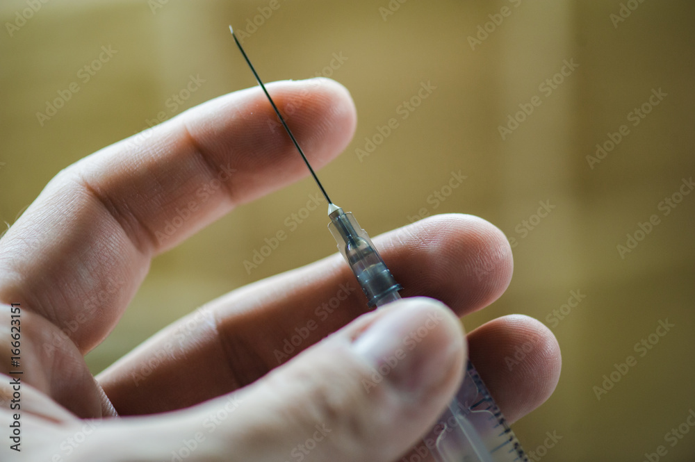 The doctor holds a syringe with a needle in his hand The doctor holds a syringe with a needle in his hand