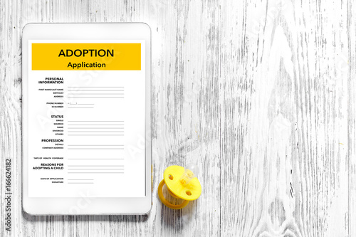 Adoption application near baby pacifier on light wooden table background top view copyspace photo