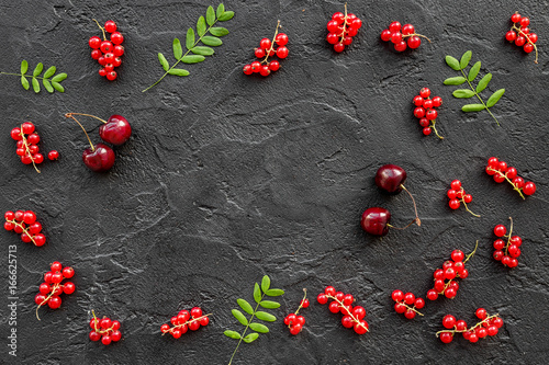 Berry frame. Red currant and leaves on black table background top view copyspace