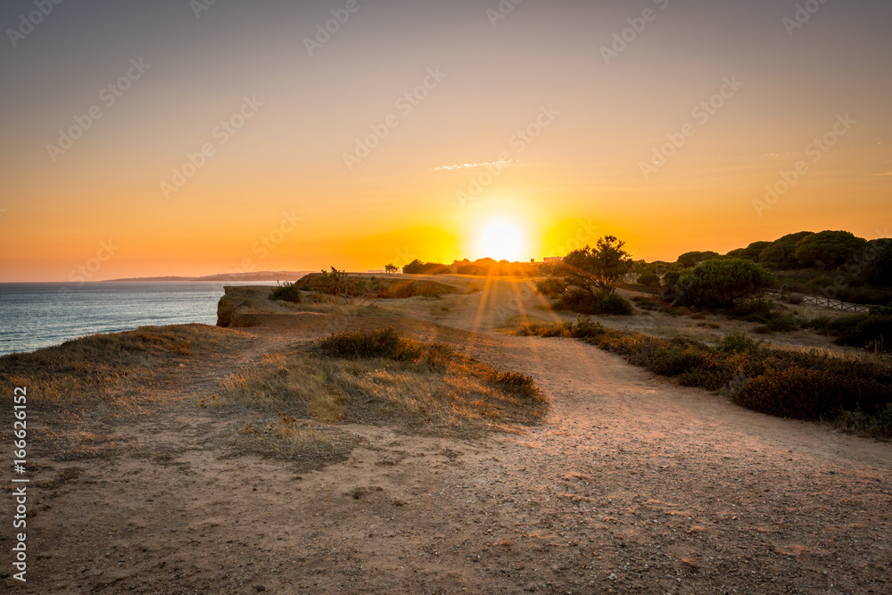 Beautiful colorful sunset in Algarve Portugal. Peaceful  water and cliffs.