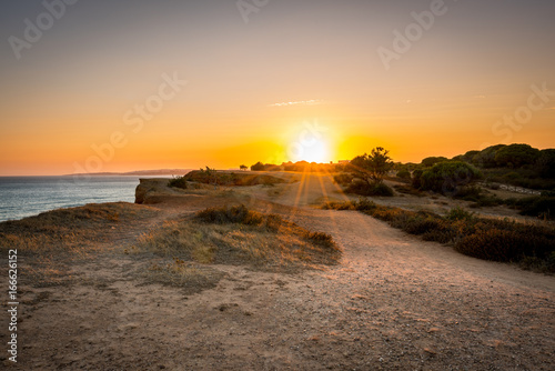 Beautiful colorful sunset in Algarve Portugal. Peaceful water and cliffs.