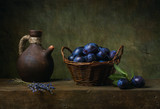 Still life with black plums in a basket on the table