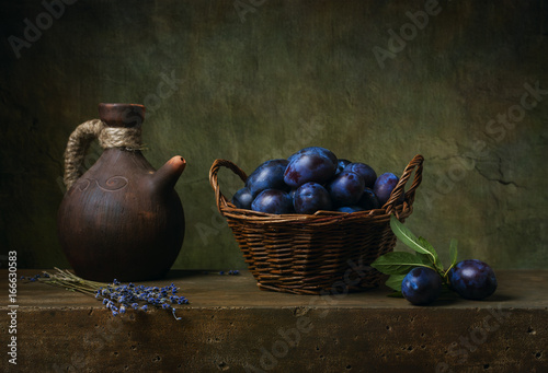 Still life with black plums in a basket on the table