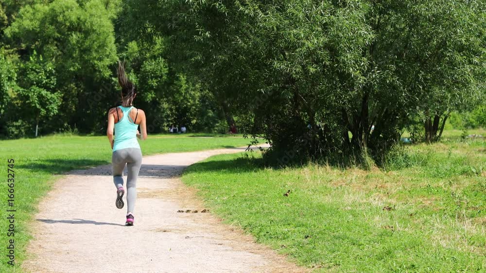 Fitness Running Women. Back view, Athletic brunette working out in summer park Fitness Running Women. Back view, Athletic brunette working out in summer park