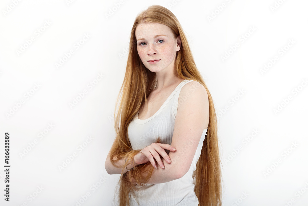 Young beautiful redhead beginner model woman in white t-shirt blue jeans practicing posing showing emotions standing against white wall background Young beautiful redhead beginner model woman in white t-shirt blue jeans practicing posing showing emotions standing against white wall background