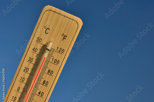 Mercury wooden thermometer shows very high temperature. Temperatures in Celsius and Fahrenheit degrees. Hot summer weather. Forty degrees over zero during the day.