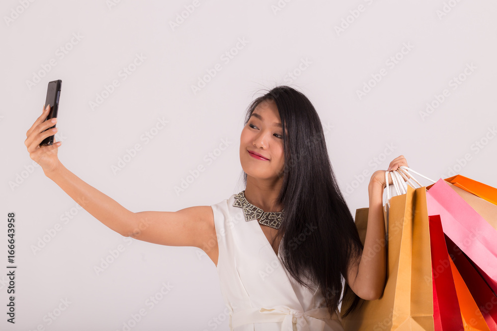 cheerful asian woman holding shopping bags and taking selfie cheerful asian woman holding shopping bags and taking selfie