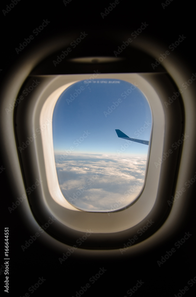 Airplane wing and blue sky through the plane's window
