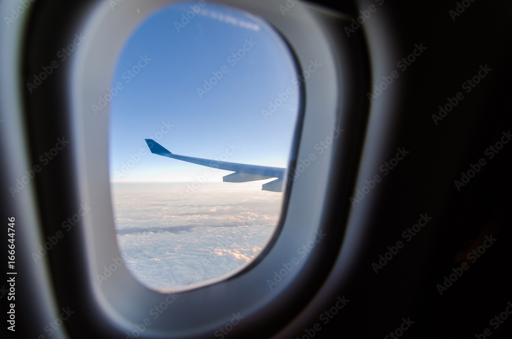 Airplane wing and blue sky through the plane's window