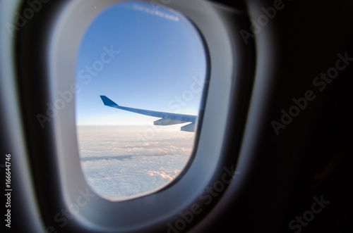 Airplane wing and blue sky through the plane s window
