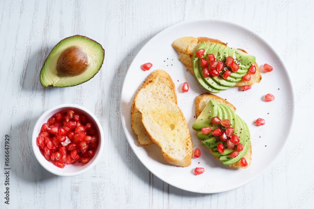 sliced avocado on toast bread with pomegranate seeds.